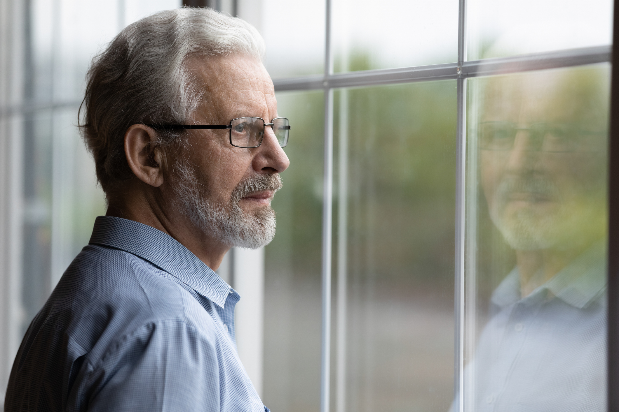Older man looking out of a window into the distance