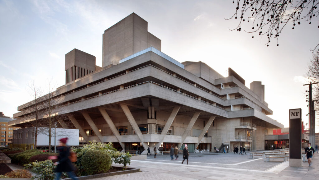 A photo of the National Theatre in London, showing the northeast corner of the building with concrete struts coming up from the ground and the different floors up to the roof.
